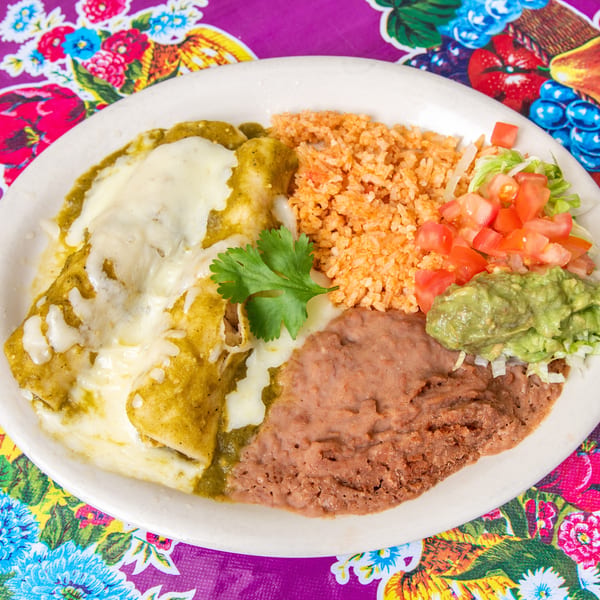 Two green enchiladas with melted cheese, rice, refried beans, guacamole, and pico de gallo.